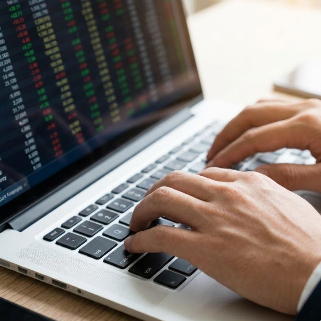 Two professional business partners in suits exchange a handshake in a bright, modern corporate office.